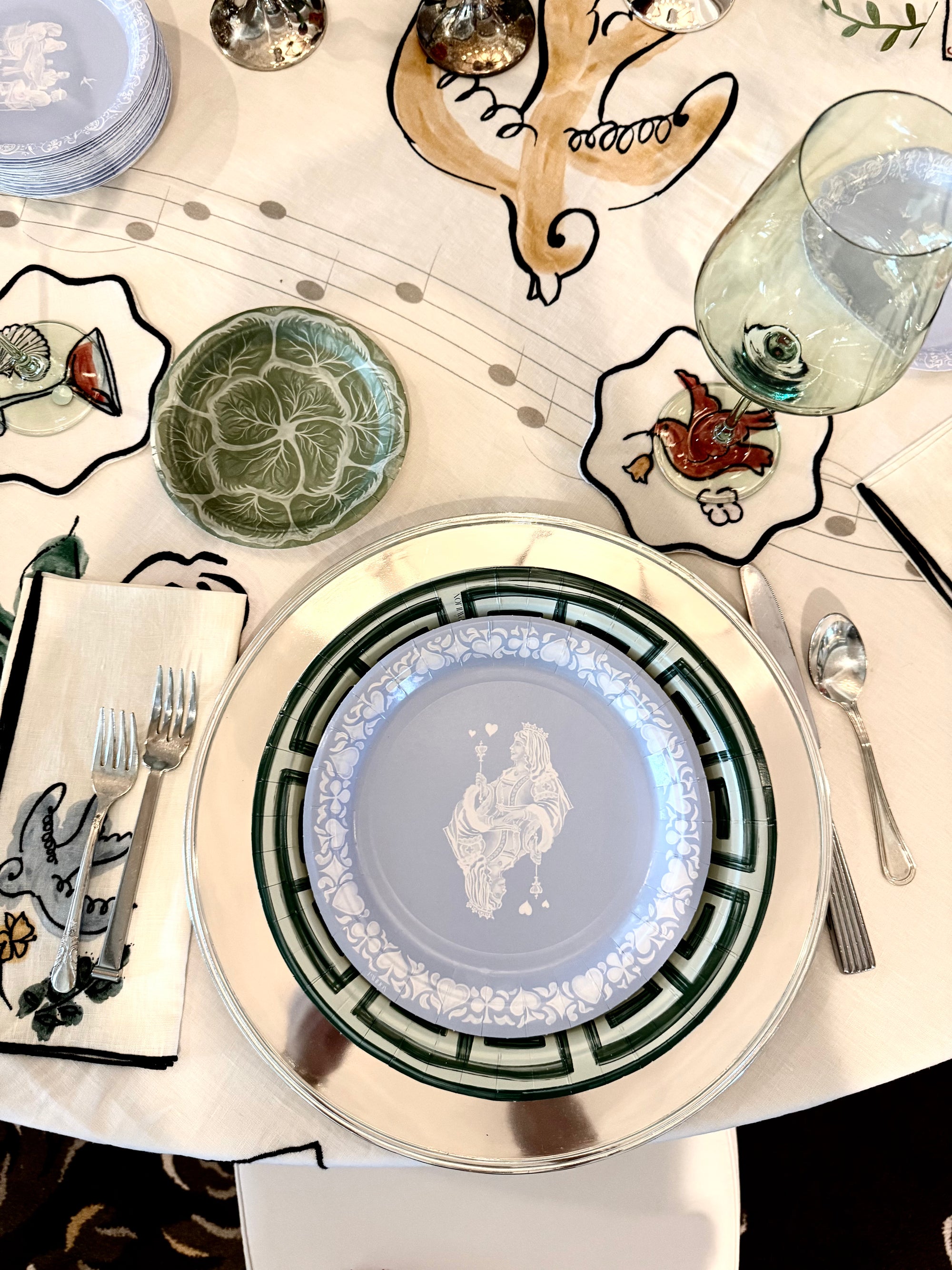 Decorative table setting with patterned plates, glasses, and cutlery on a white tablecloth.
