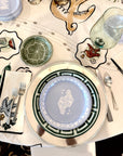 Decorative table setting with patterned plates, glasses, and cutlery on a white tablecloth.